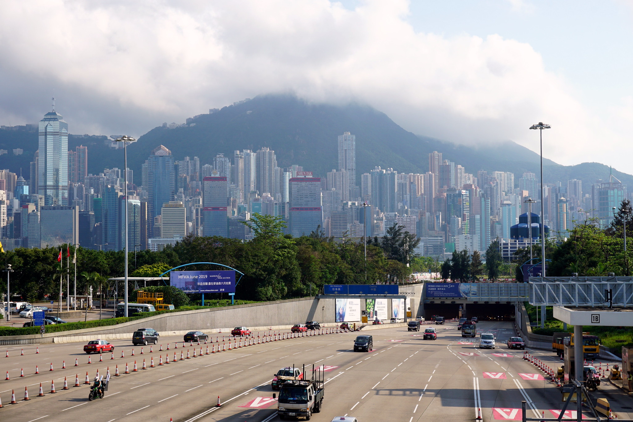 A view of the traffic entering and exiting at the Kowloon side of the Western Harbour Crossing in Hong Kong. There are red taxis, a minibus, private cars and a motocycle among the vehicles at the tunnel.