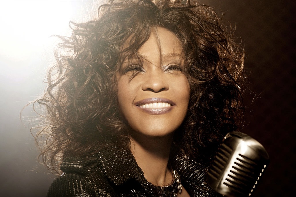 A close-up of Whitney Houston holding a studio microphone.