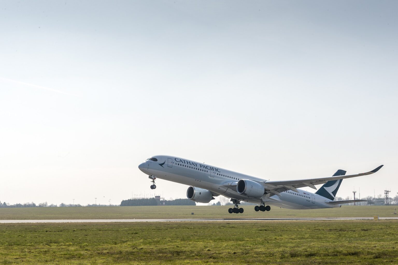 A Cathay Pacific flight takes off from Brussels Airport. The plane has just taken off and it hasn't yet retracted its landing gear.