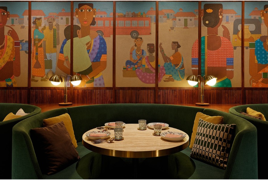 the green velvet booth seats with a backdrop of colorful mural at chaat
