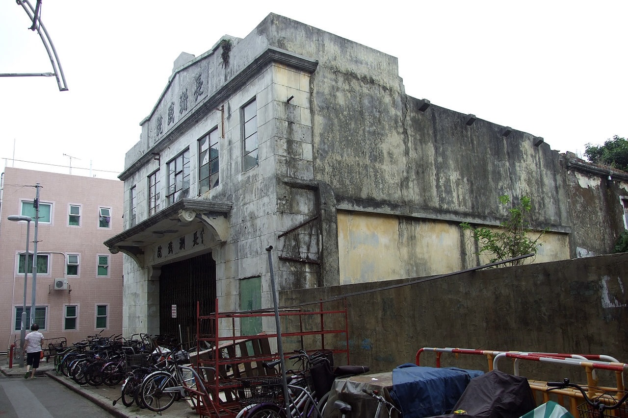 The facade of the old Cheung Chau Cinema in 2010. The cinema fell into disuse, which is evident in its discoloured and mottled walls. There are bicycles parked in front of the entrance.