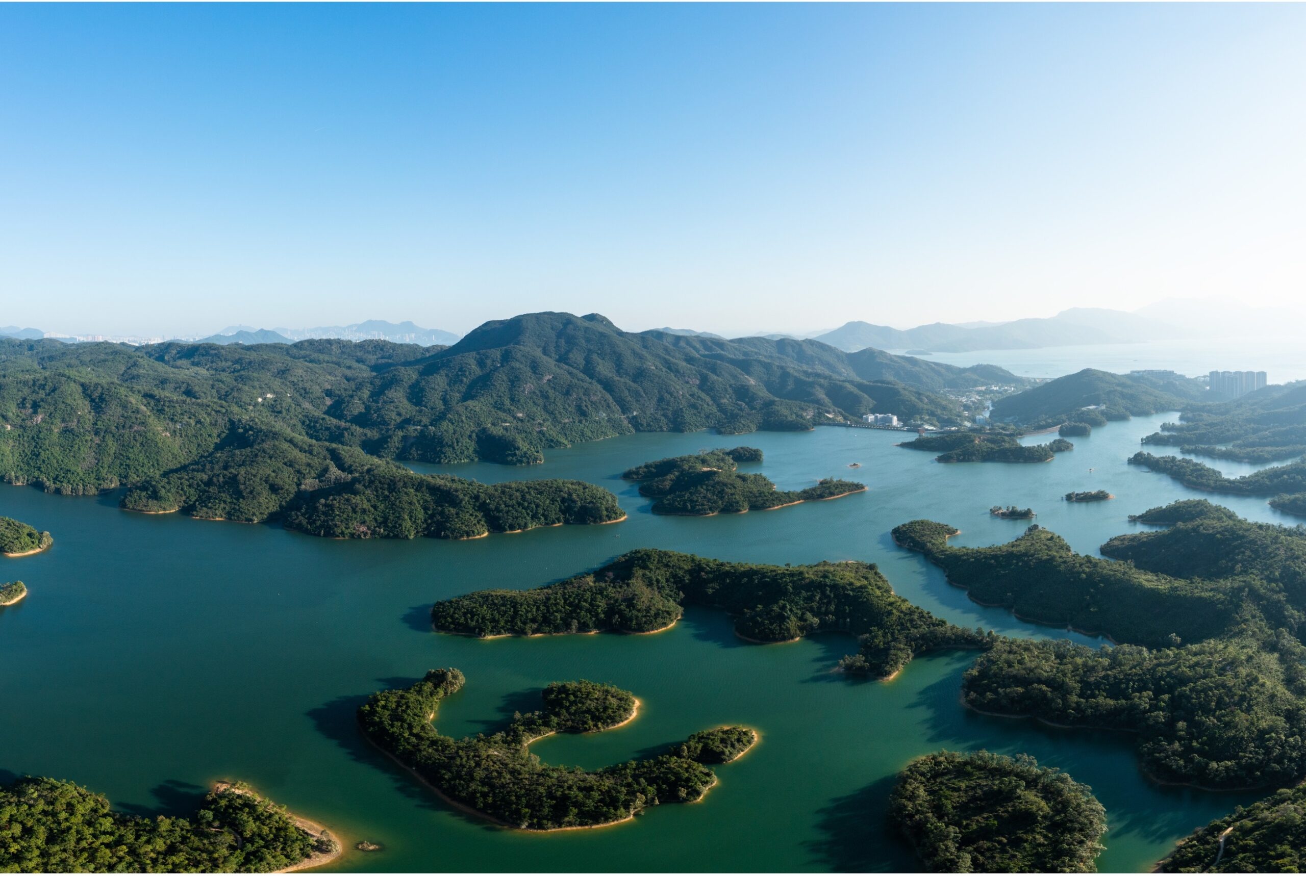 An overhead view of the islands within Tai Lam Chung Reservoir at Tai Lam Country Park. The islands are green with sandy shores and are of different shapes.