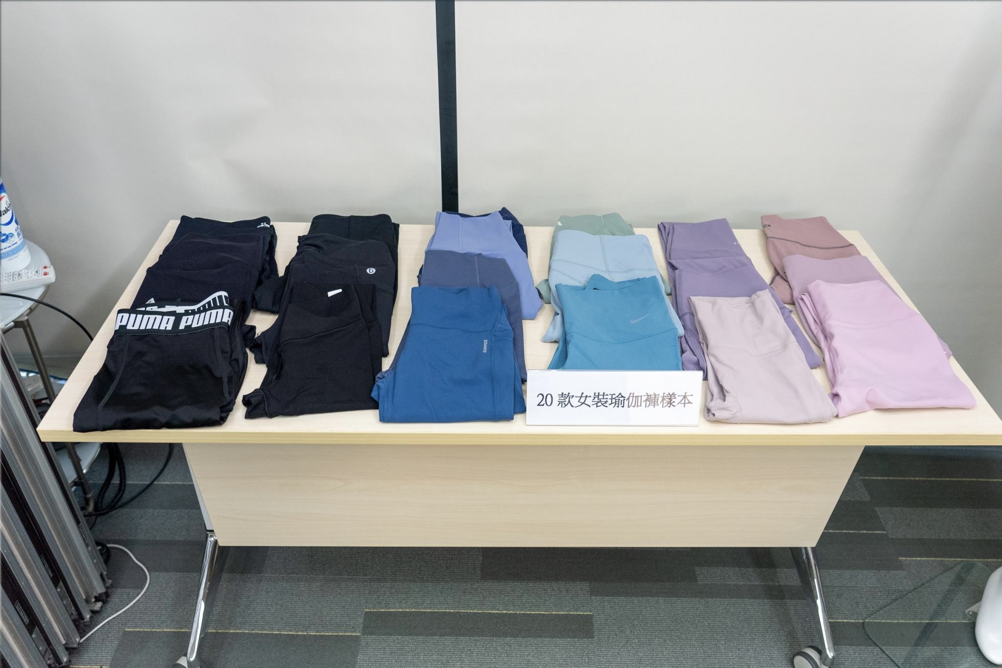 Twenty models of yoga pants displayed on a table. The pants vary in terms of colour, though most are in shades of blue or black.