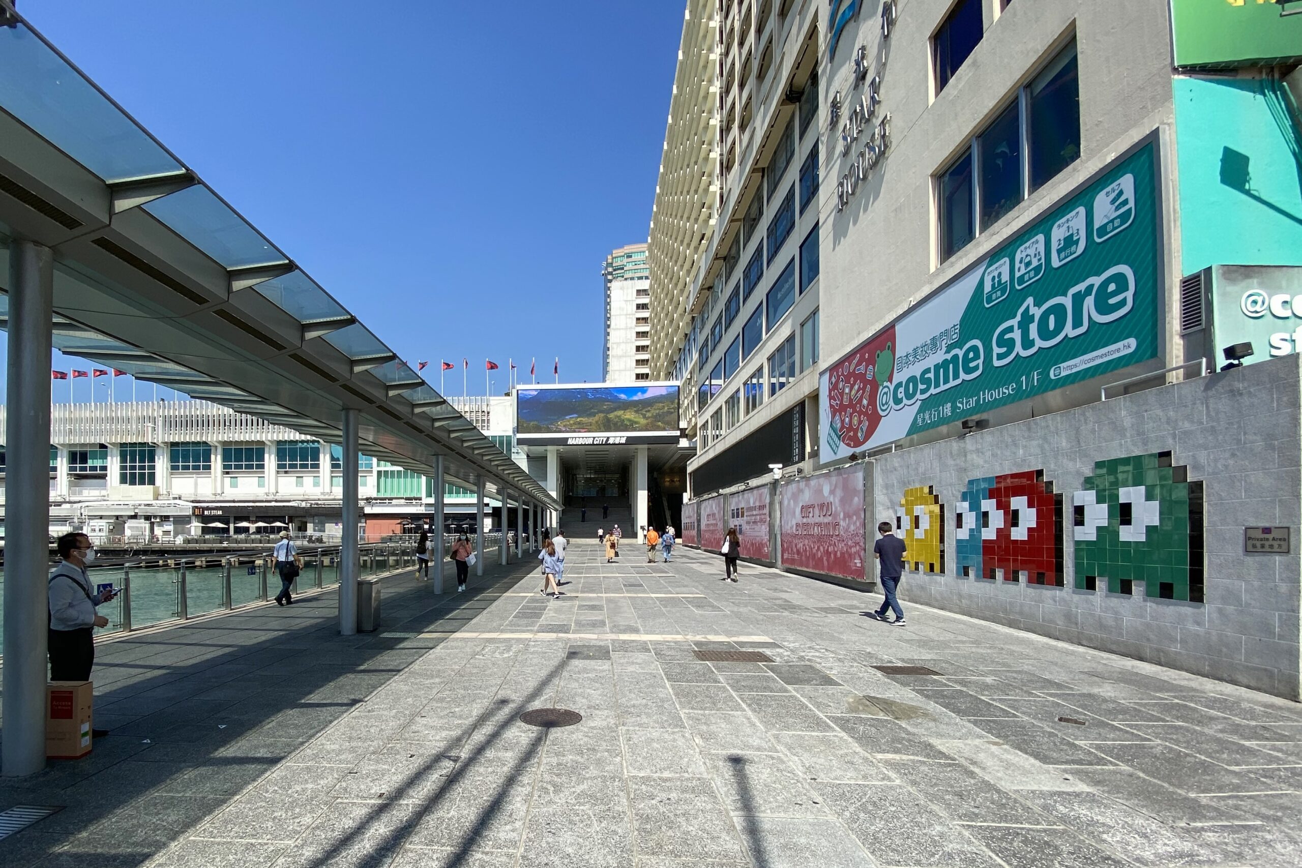 The entrance to Harbour City mall in Hong Kong. On the left is Victoria Harbour and on the right are the four Pac Man ghosts on a wall that lead up to the mall.