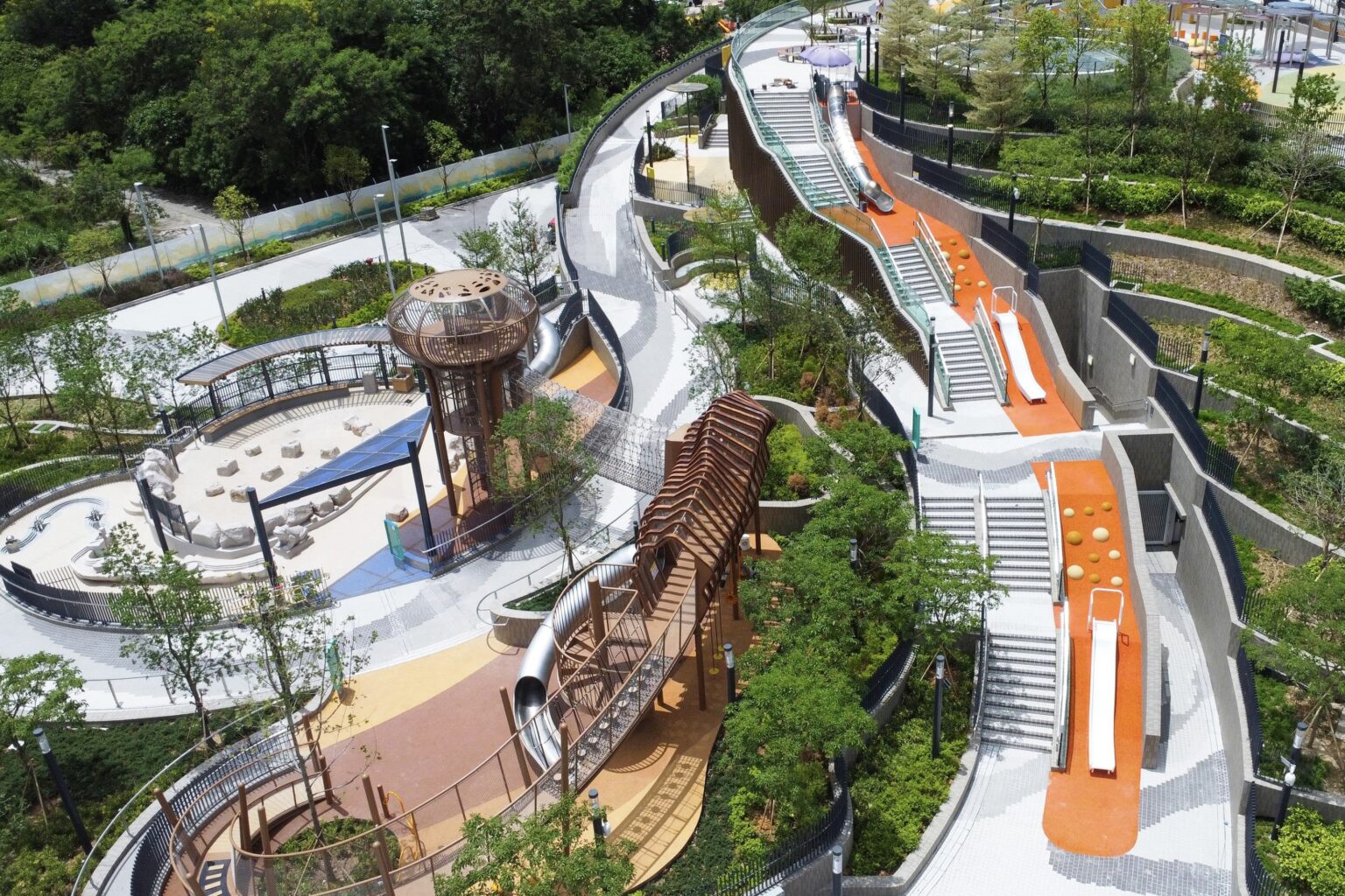 An overhead view of the landscaped deck at the Cha Kwo Ling Promenade. There are slides, a rope tunnel bridge, and a series of steps connecting the various levels of the deck.