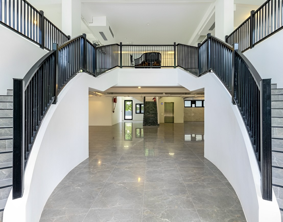 There are two grand staircases that lead to an open layout. The home has marble flooring. A grand piano can be seen on the upper floor of the house.