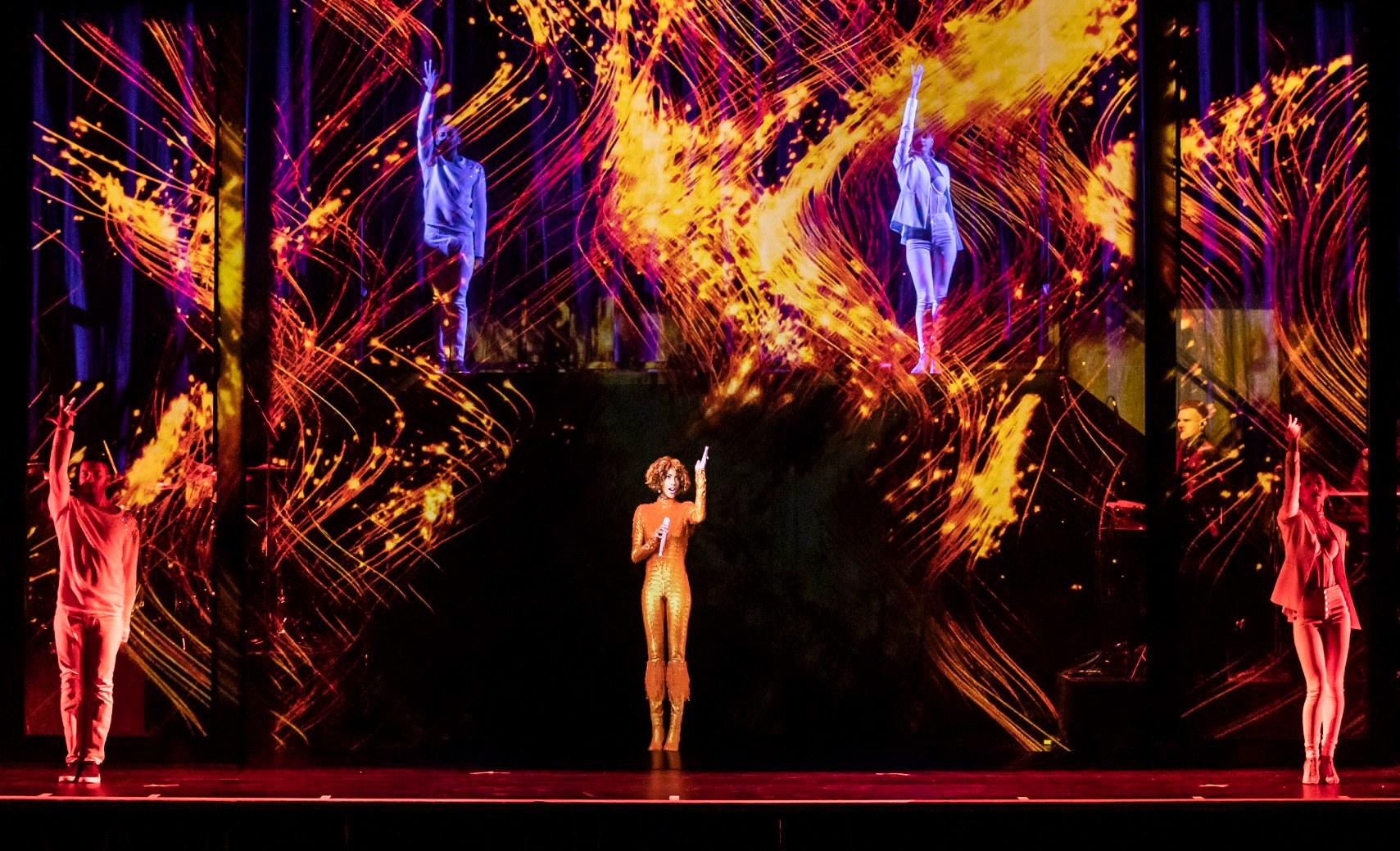 A holographic image of the late Whitney Houston stands centre stage, surrounded by backup dancers.