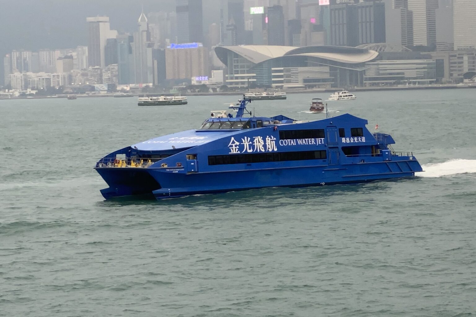a blue cotai water jet ferry goes from hong kong to macau on victoria harbour