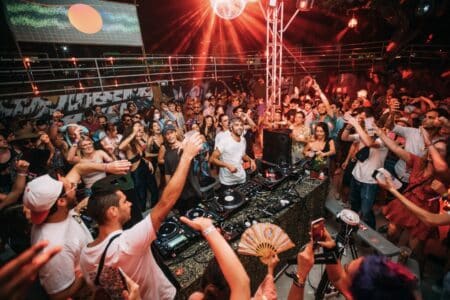 A DJ is surrounded by attendees of a music festival.