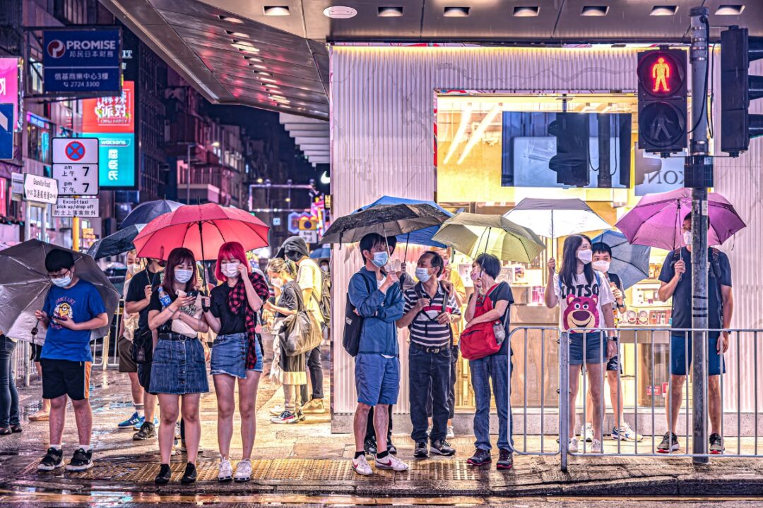 people at a street crossing on a rainy hong kong night