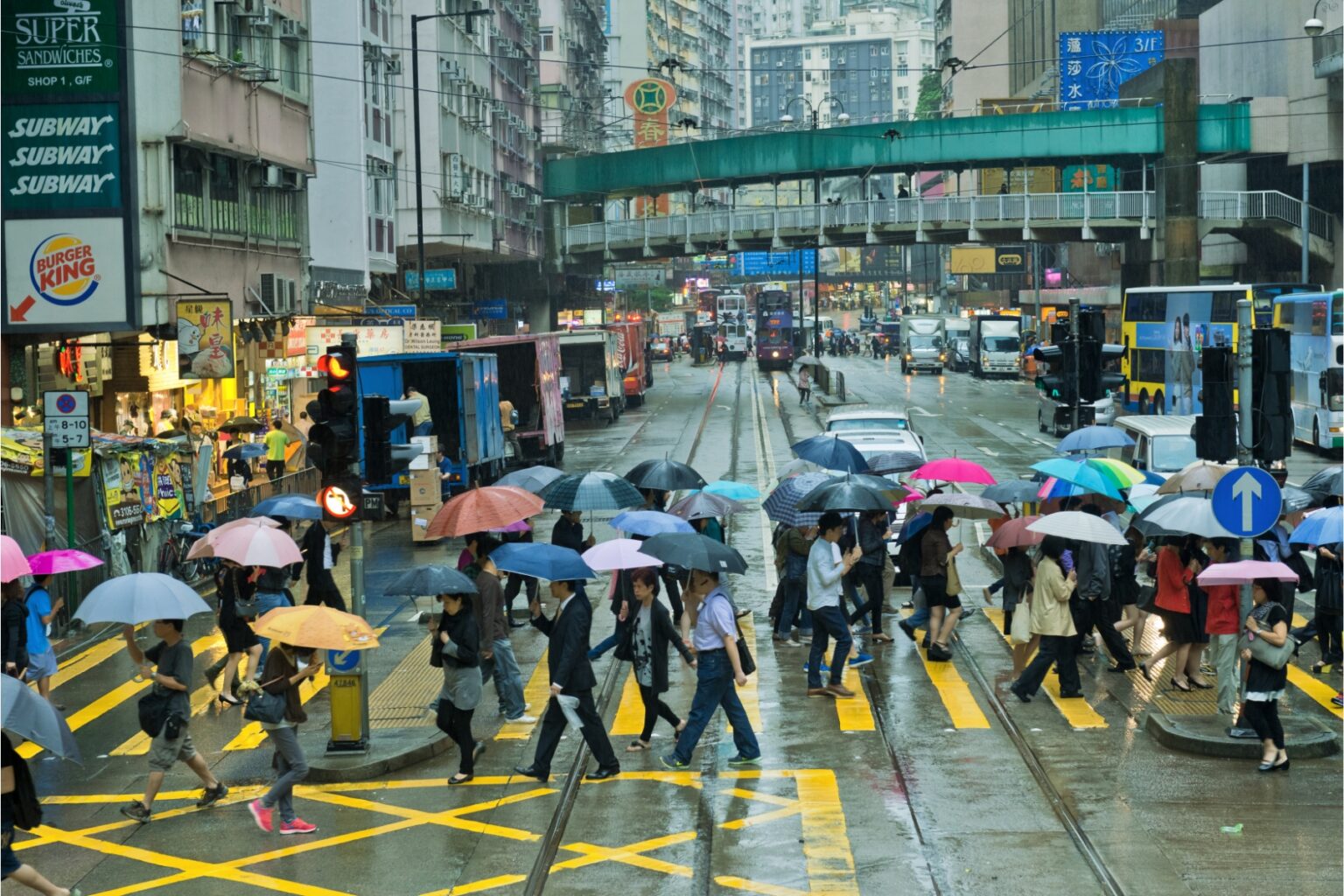 people crossing a busy street in hong kong on a rainy day