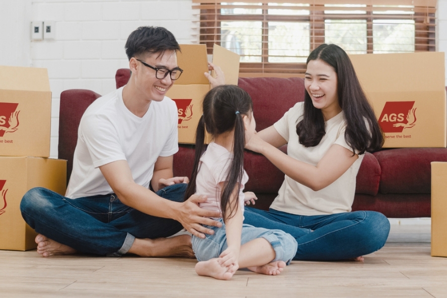 family of three in front of a sofa with AGS movers boxes