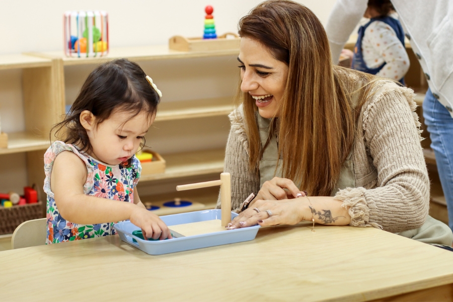 a toddler and teacher at a table in a montessori environment