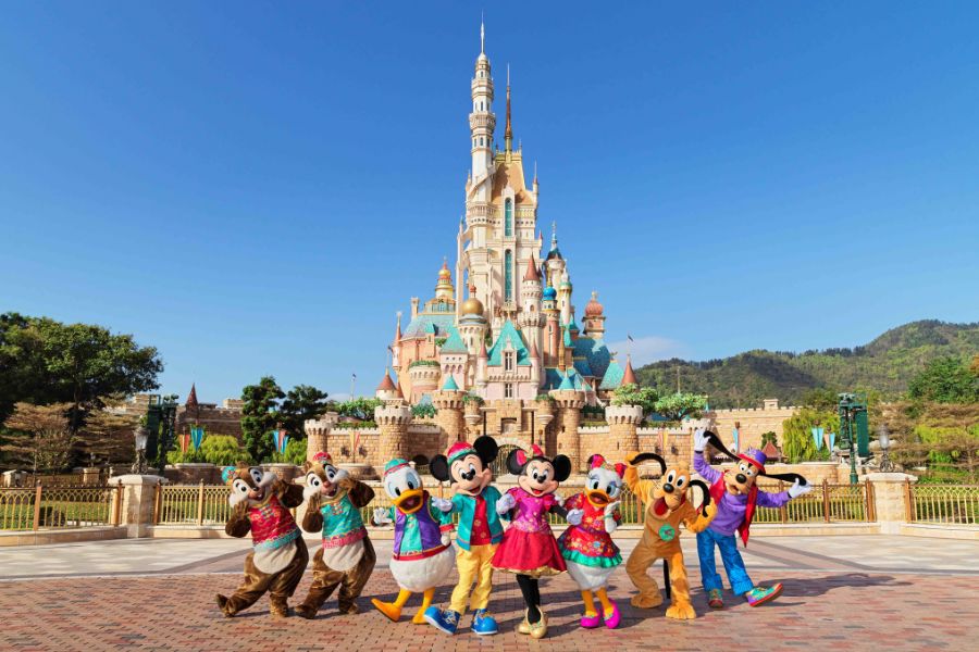 Disney characters posing together in front of castle